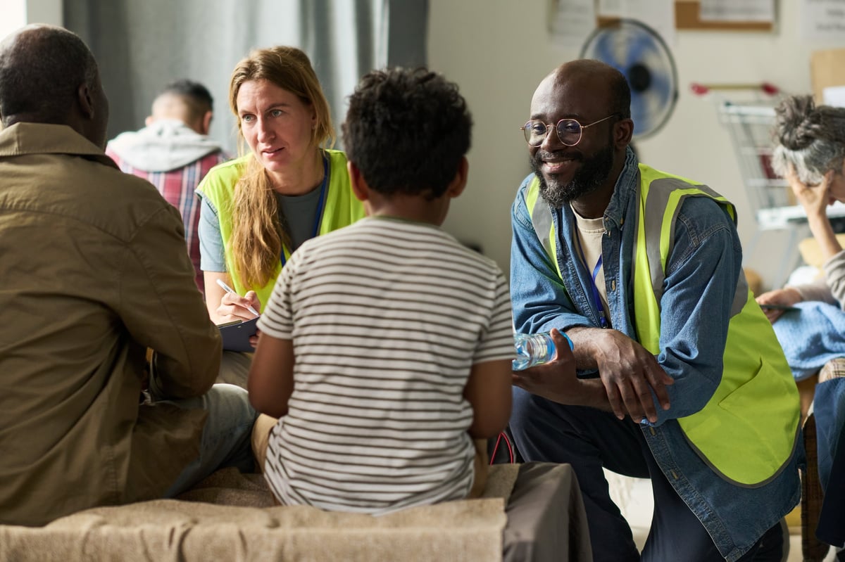 Voluntarios escuchando con atención a una familia en un centro de apoyo comunitario
